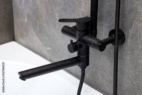 A sleek black faucet featuring a hose that is firmly attached to it
