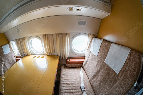 Older yellow and tan interior airplane, open cockpit curtain reveals sky view Control panel with switches, closed curtains cockpit separation, unoccupied crew area brown seats Even artificial l