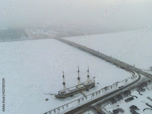 An aerial view showing a historic frigate near the Palace Bridge over the frozen Neva River in Saint Petersburg