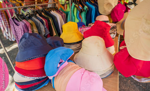 Fototapeta Naklejka Na Ścianę i Meble -  Colorful traditional hats display at rural Thai street market where local vendors sell handmade headwear to tourists during sunny day creating vibrant shopping experience in countryside Thailand