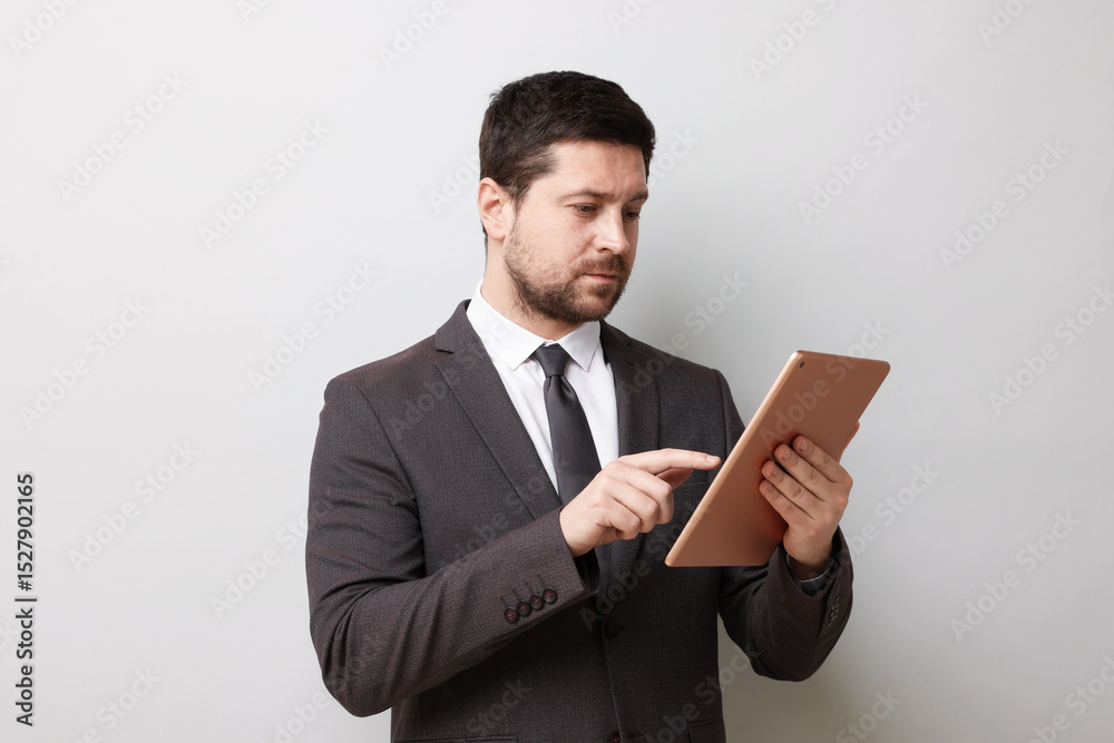 Handsome businessman using tablet on light grey background Handsome businessman using tablet on light grey background