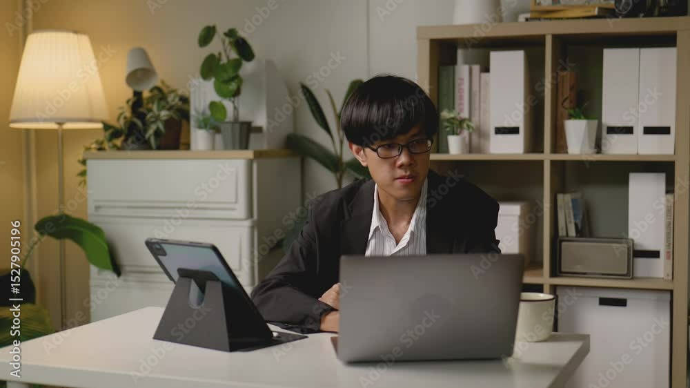 Asian businessman attending an online video meeting from his home office while sipping coffee.4k Asian businessman attending an online video meeting from his home office while sipping coffee.4k