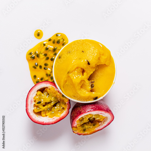 Mango passion fruit sorbet sits in a bowl next to a halved fruit, highlighting its juicy goodness