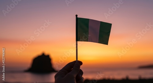 Patriotic display: Nigerian flag held aloft against vibrant sunset backdrop