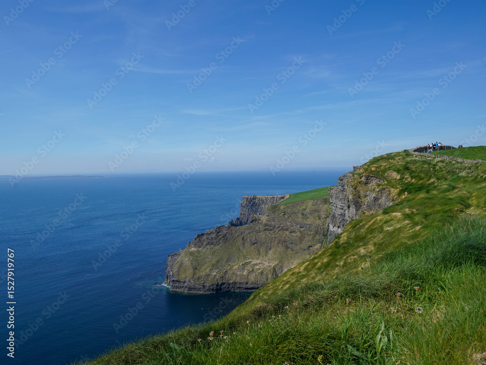 Fototapeta premium Steep cliffs rise dramatically above the deep blue ocean under a clear sky