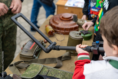 Child learns about military equipment at an outdoor event showcasing defense technology and safety practices in a public park