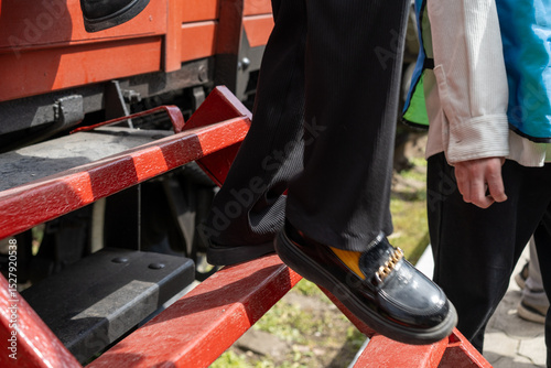 Person stepping down from train stairs in a bright outdoor setting during a sunny day