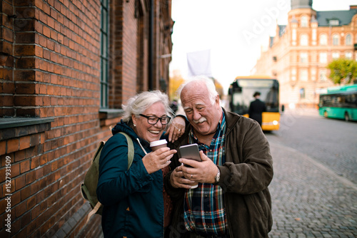 Happy senior couple taking selfie on vacation in European city street