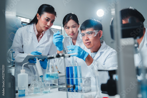 A diverse team of young scientists conducts a chemistry experiment, carefully analyzing blue liquids in test tubes, demonstrating teamwork, focus, and precision in a modern laboratory setting.