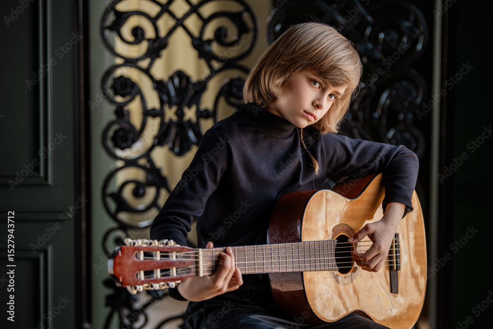 Obraz premium Young Boy Playing Acoustic Guitar with Focused Expression