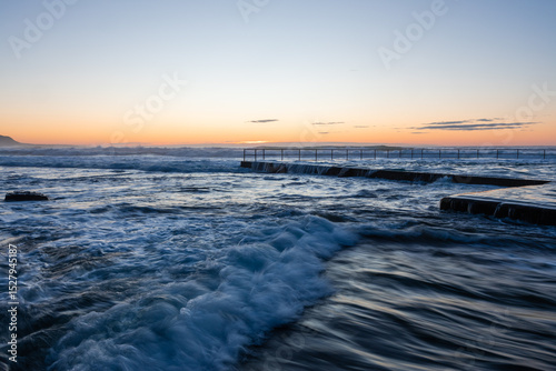 Flowing high tide water around Wombarra rock pool, Australia.