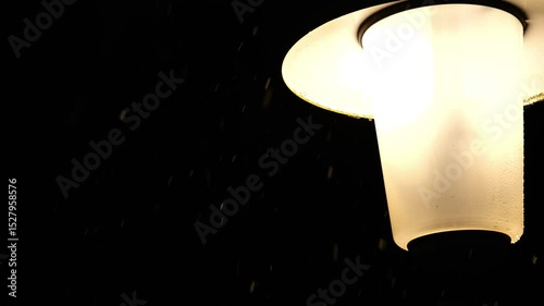 Lantern and falling snow in the night sky.Snowflakes in the light of a lantern in the dark.Snowy winter weather. 4k footage