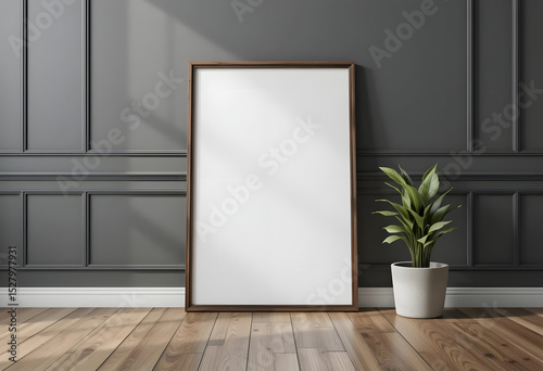 Empty picture frame mockup leaning against a dark grey wall with a potted plant.