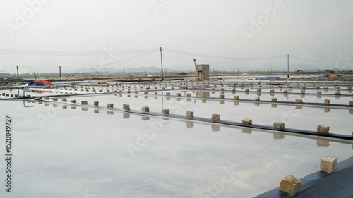 Wide view of salt fields in Vietnam Hon Knoi village. Expansive evaporation pans, traditional production, rural coastal landscape, organized crystallization pools, rural economy, local extraction