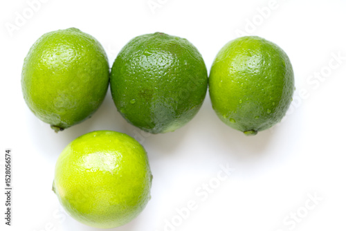 Fresh, vibrant green limes on a clean white surface. Juicy citrus fruits symbolizing summer freshness and healthy living. Selective focus creates a bright, inviting mood.