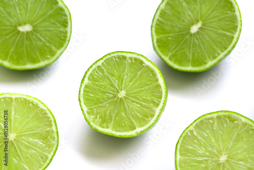 Vibrant green lime halves arranged on a clean white surface. The juicy texture and vivid color evoke a sense of freshness, summer, and natural simplicity. Selective focus.