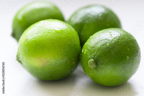 Fresh, vibrant green limes on a clean white surface. Juicy citrus fruits symbolizing summer freshness and healthy living. Selective focus creates a bright, inviting mood.
