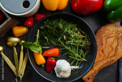 Making a vibrant Cajun Spice Blend, mixing red paprika, cayenne pepper, oregano, thyme, white garlic onion powder and black pepper in a bowl, creating a striking contrast against a black background.