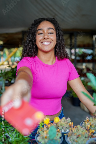 Young woman paying with credit card, buying plants at flower shop