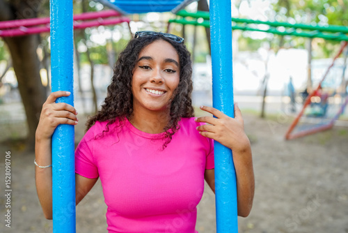 Young woman smiling and holding playground bars in a park