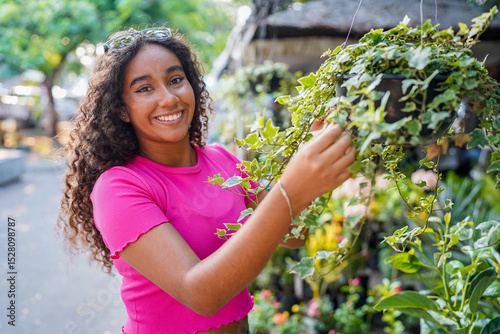 Young woman choosing a hanging plant in a plant shop