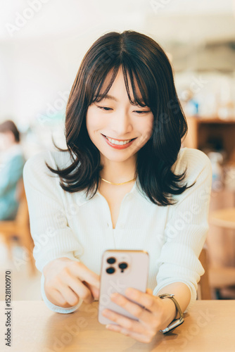 カフェでスマホを使う笑顔の女性