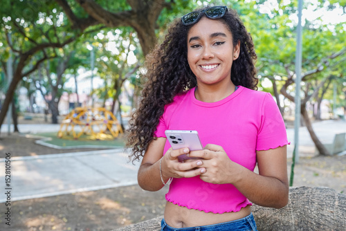 Young latin woman using smartphone in a park