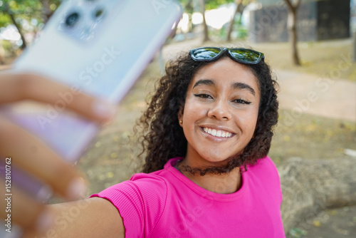 Young woman taking a selfie with smartphone in a park
