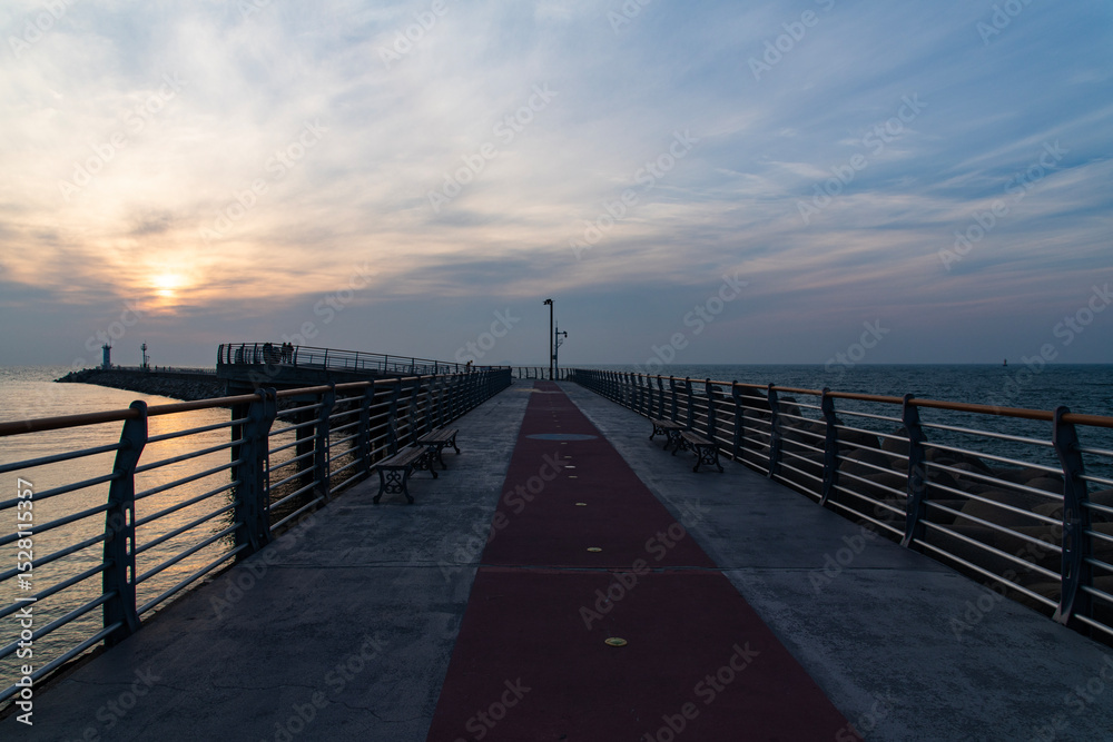 Obraz premium walkway on the seawall at the harbor during sunset