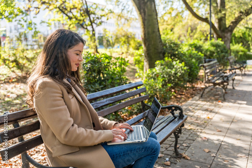 Professional occupation woman sitting on park bench, focused on laptop work blending outdoor relaxation with productivity showcasing modern remote working digital nomad lifestyle and urban tranquility