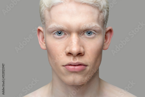 Close up portrait of albino man, blue eyes, white hair, grey background, high detail. 5000 px