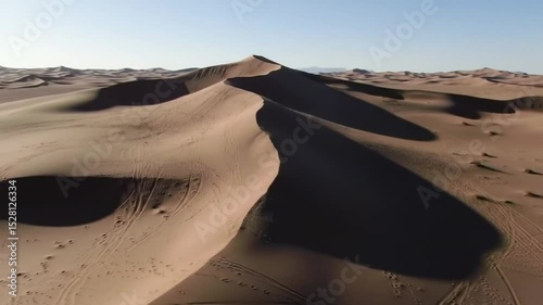 Majestic Desert Landscape Featuring Rolling Sand Dunes Under a Clear Blue Sky with Tire Tracks Showing Off-Road Adventure