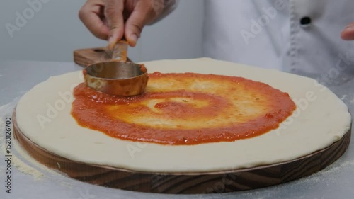Tomato sauce preparing pizza on the table 