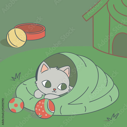 Playful gray kitten peeking out from cozy blanket in garden 