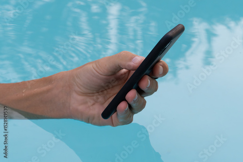Hands using smartphone in swimming pool. 