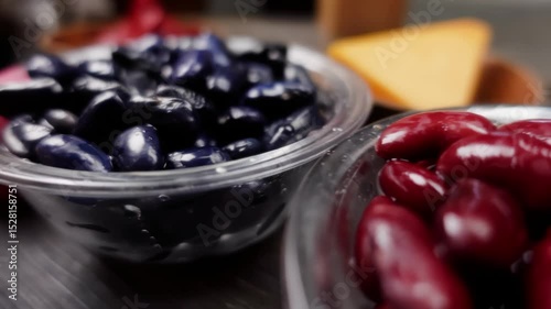 A closeup panoramic view of separate white bowls containing raw black beans and red kidney beans. These are key protein rich ingredients for preparing a hearty homemade chili con carne meal