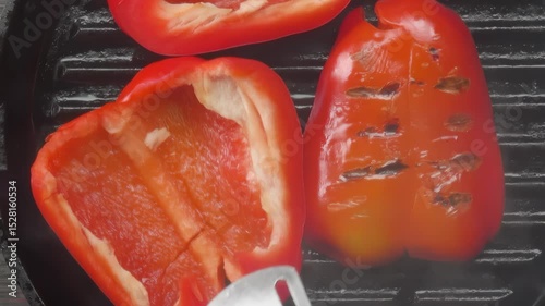 Metal kitchen tongs flip slices of fresh red bell pepper on a hot black grill pan. Top down view of a healthy vegetarian cooking process for a delicious summer meal or appetizer