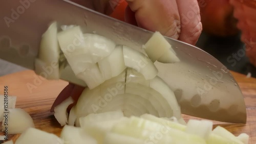 A macro or closeup shot of a kitchen knife carefully slicing a fresh raw onion. Preparing ingredients for a healthy and delicious homemade meal in the kitchen