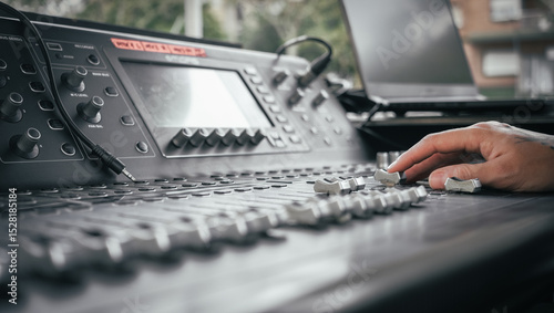 the hand of a tattooed person controlling a sound mixer at a live event