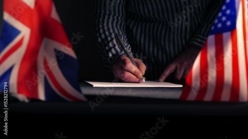 Hand signing a trade deal with American USA flag and British Union Jack