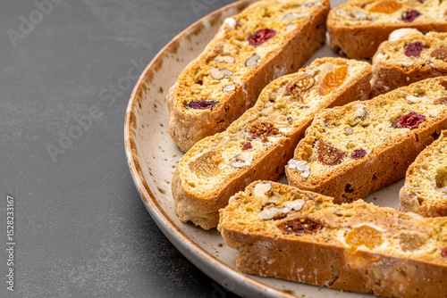 Italian Almond Biscotti biscuits in a rustic home made pottery bowl. Studded with almonds and cranberries, these twice-baked treats are aromatic and inviting. Ideal.