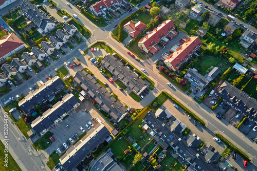 Fototapeta Naklejka Na Ścianę i Meble -  Aerial view of residential suburban area with rows of houses, streets and green backyards. European neighborhood in small town