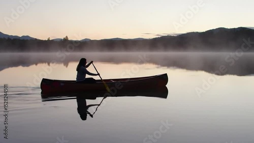 Canoe on Still Lake with Mist and Mountains at Dawn