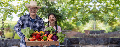 Farmer holding wooden box full of fresh vegetables. Basket with vegetable. Man and Daughter holding big box with different fresh farm vegetables.