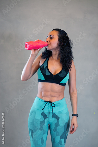 Mulher sarada bonita tomando água na academia