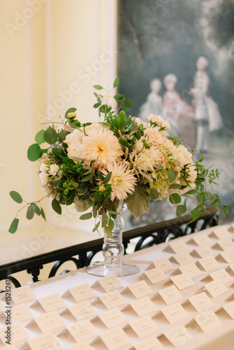 Elegant floral arrangement displayed on a table with place cards at a formal event in a beautiful venue