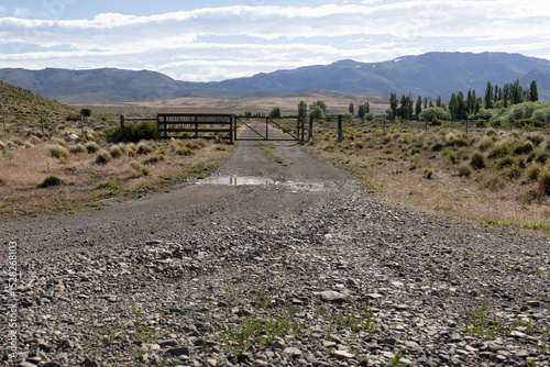 Landscape in a Patagonian ranch with a wooden gate on a gravel road