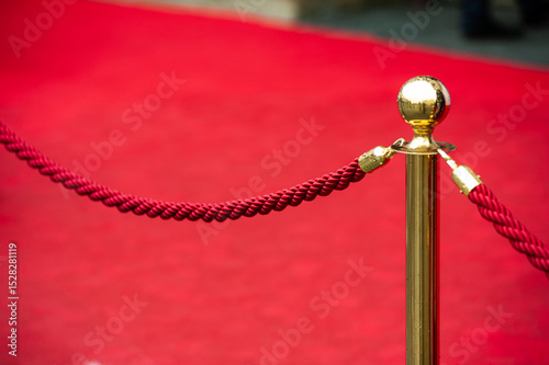 Red carpet event barrier with gold stanchions and red rope, luxury entrance to VIP zone or exclusive ceremony, elegant festive setting for celebrity gala or formal award show