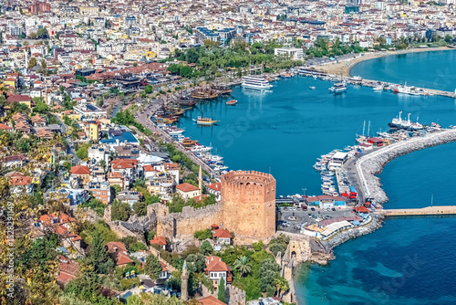 Aerial view of Alanya's Red Tower and harbor with boats, historic fortifications, and vibrant cityscape along the Mediterranean coast in Turkey, highlighting the area scenic beauty and rich heritage