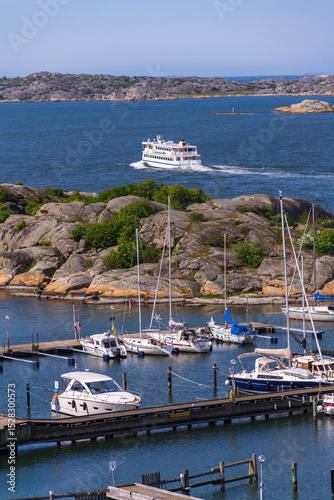 Archipelago ferry leaving harbour with ships at Saltholmen peninsula on the shore of Alvsborgsfjorden, Alvsborg district, Gothenburg, Sweden, sunny day